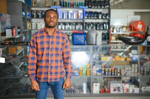 portrait de une Beau africain vendeur dans un auto les pièces magasin. le concept de voiture réparation photo