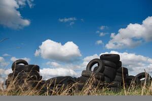 vieux utilisé pneus empilés avec haute pieux. environnement la pollution concept photo