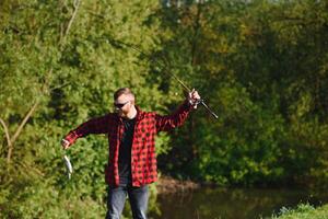 pêcheur par le rivière avec une capture de poisson. homme pêcheur détient dans main poisson. photo