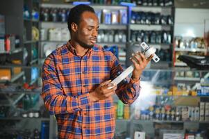 portrait de une Beau africain vendeur dans un auto les pièces magasin. le concept de voiture réparation photo