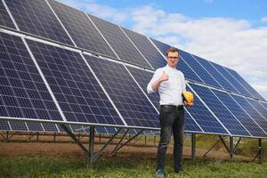 solaire énergie. Jeune affaires homme dans une blanc chemise près le solaire panneaux à Puissance les plantes. photo