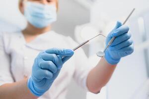 portrait de une dentiste en portant dentaire instruments dans le sien mains dans le clinique fermer photo