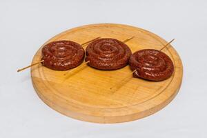 saucisse rôti sur le gril sur une rond planche isolé sur une blanc Contexte photo