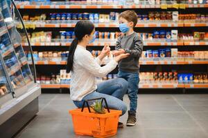 femme désinfecte sa fils mains dans le boutique pendant coronavirus et grippe épidémie. photo
