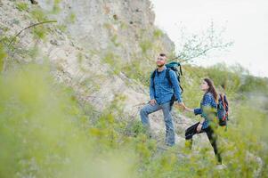 promeneur gars donne une main à le fille tandis que en marchant dans le montagnes, Aidez-moi et relation amicale concept photo