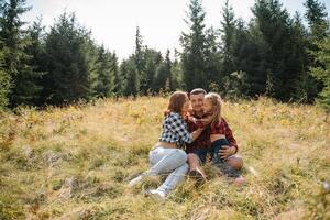 famille de Trois gens du repos dans le montagnes. elles ou ils Sam vers le bas à repos, boisson l'eau après une difficile montée à le Montagne. elles ou ils sont fatigué mais content photo