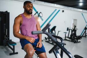 africain homme en utilisant Stationnaire vélo dans une Gym photo