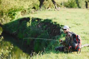 Jeune pêcheur des poissons près le rivière. le concept de Extérieur Activités et pêche photo