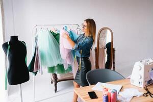 attrayant femelle mode designer est travail dans sa atelier. élégant femme dans processus de création Nouveau vêtements collection. photo