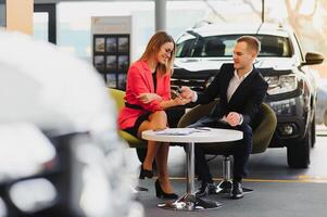 magnifique Jeune femme achète une voiture dans le concession salon. photo