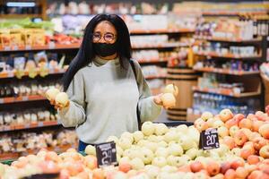 africain femme portant jetable médical masque. achats dans supermarché pendant coronavirus pandémie épidémie. épidémie temps photo