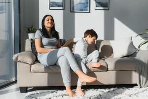 Jeune mère avec sa 4 ans vieux peu fils habillé dans pyjamas sont relaxant et en jouant dans le lit à le fin de semaine ensemble, paresseux matin, chaud et confortable scène. photo