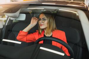 Jeune femme à la recherche dans le vue arrière miroir de une voiture photo