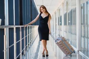 Jeune femme avec bagage à le international aéroport. elle est très content de sa vacances à chaud pays sur Noël vacances photo