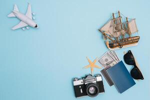 préparation pour en voyageant concept, montre, avion, argent, passeport, des crayons, livre, photo cadre, monocle sur bleu Contexte avec copie espace.