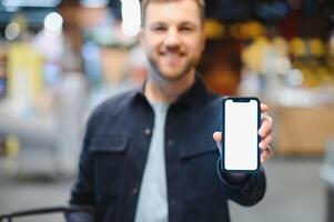 homme en utilisant téléphone intelligent dans supermarché. photo