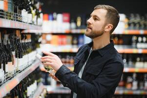 homme dans une supermarché choisir une du vin photo