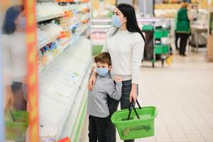 portrait de une mère et sa peu fils portant protecteur visage masque à une supermarché pendant le coronavirus épidémie ou grippe épidémie. vide espace pour texte photo