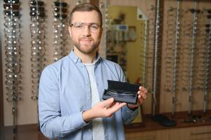 Jeune homme choisir lunettes à optique magasin photo
