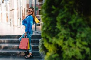 magnifique fille avec achats Sacs est à la recherche à caméra et souriant tandis que Faire achats dans le centre commercial photo