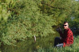 pêcheur homme pêche avec filage barre sur une rivière banque, tourner pêche, proie pêche photo