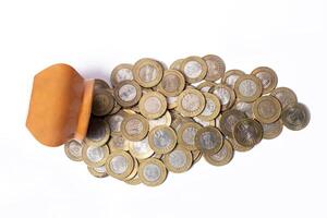 pièces de monnaie effusion en dehors de une argile pot isolé sur blanc Contexte. économie concept. photo