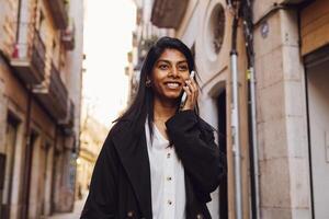 Jeune femme en marchant par le ville en utilisant une dispositif photo