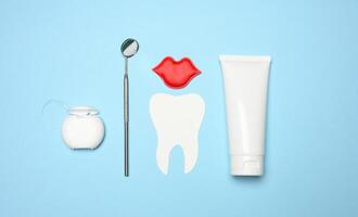 tube avec dentifrice, dentaire soie et dentiste miroir sur bleu Contexte photo