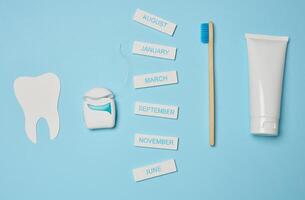 tube avec dentifrice, dentaire soie et brosse à dents sur une bleu arrière-plan, oral hygiène. photo