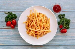 lacet français frites avec un barbecue sauce, mer sel et tomates dans blanc assiette sur en bois table Contexte Haut vue côté plat photo