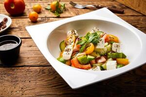 méditerranéen salade avec concombre, tomate, basilic et fromage cube servi dans plat isolé sur en bois table avec brut nourriture Haut vue de super en bonne santé apéritif nourriture photo