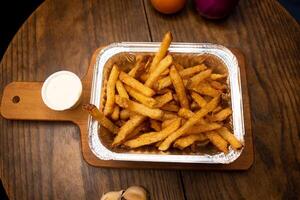 ordinaire français frites avec mayo tremper servi dans plat isolé sur en bois planche Haut vue de Fast food photo