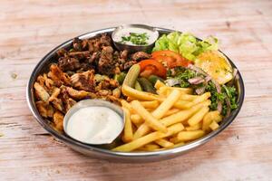 mélanger laham, bœuf, poulet, dajaj shawarma plat avec frites et salade servi dans plat isolé sur table Haut vue Fast food photo