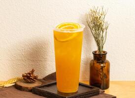 glacé Frais Orange vert thé servi dans jetable verre isolé sur en bois planche côté vue de taiwanais la glace boisson photo