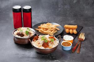 Indien épicé poulet biryani double traiter avec pouvez boire, frites et raita servi dans une plat côté vue sur gris Contexte photo