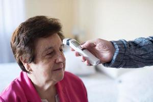 femme caucasienne de plus de 70 ans lors du contrôle de la température pour covid-19 à la maison photo