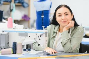 portrait de une magnifique couturière porter une ruban mesure et travail dans une textile usine photo