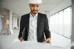 Indien construction site directeur permanent portant casque, en pensant à construction placer. portrait de mixte course Manuel ouvrier ou architecte. photo