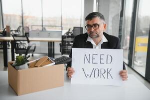 vieux employé en quittant Bureau avec le boîte plein de affaires photo