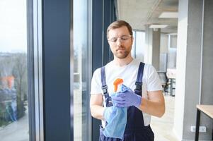 un employé de une professionnel nettoyage un service lavages le verre de le les fenêtres de le bâtiment. vitrine nettoyage pour magasins et entreprises. photo