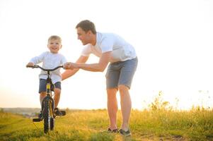 du père journée. papa et fils en jouant ensemble en plein air sur une été. content famille, père, fils à le coucher du soleil. photo