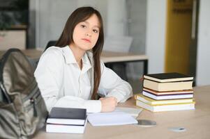 une mignonne écolière est séance à une bureau à école. le concept de scolarité. photo