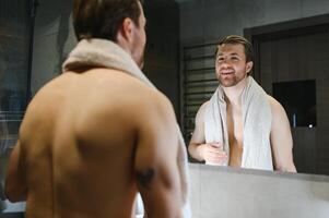 Jeune homme à la recherche dans miroir après rasage à Accueil photo