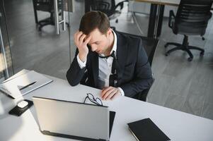 portrait de stressé en dehors et inquiet gênant surmené homme d'affaire entrepreneur à la recherche les documents rapport dans moderne brillant Bureau travail en dessous de pression et serré date limite photo