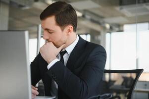 concentré sérieux homme d'affaire dans costume en pensant en train de lire en ligne nouvelles ou résolution affaires problème travail sur portable à la recherche à filtrer, inquiet perplexe exécutif gérant Stock marché des risques en utilisant ordinateur photo