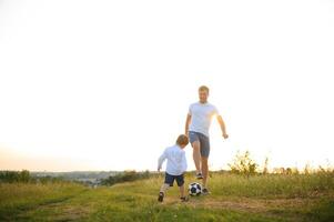 Jeune père avec le sien peu fils en jouant football, du père journée. photo