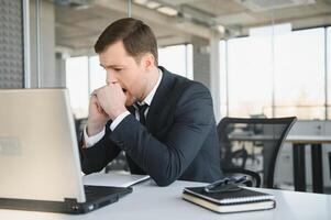 déprimé Jeune homme d'affaire en portant tête dans mains, a problème, une portable sur le bureau. une gars fabriqué une erreur dans une travail photo