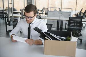 triste licencié. laisser aller Bureau ouvrier packs le sien affaires dans papier carton boîte et feuilles bureau. la main d'oeuvre réduction, réduction des effectifs, réorganisation, restructuration, externalisation. Masse chômage marché crise photo