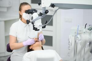 femelle dentiste en utilisant dentaire microscope traiter patient les dents à dentaire clinique Bureau photo