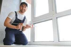 Beau Jeune homme installation baie fenêtre dans Nouveau maison construction site photo